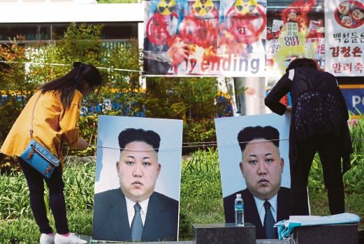 PESERTA membetulkan potret pemimpin Korea Utara Kim Jong-Un ketika perhimpunan mengecam ujian nuklear dan peluru berpandu Pyongyang di Seoul, Korea Selatan, semalam.