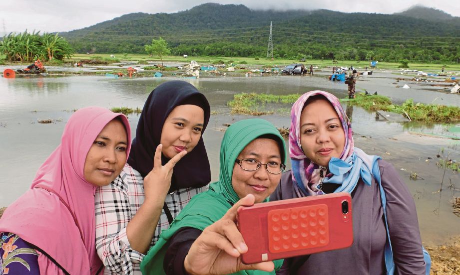 SOLIHAT dan rakannya merakam  swafoto di satu kawasan sawah yang musnah akibat tsunami di Banten. - The Guardian
