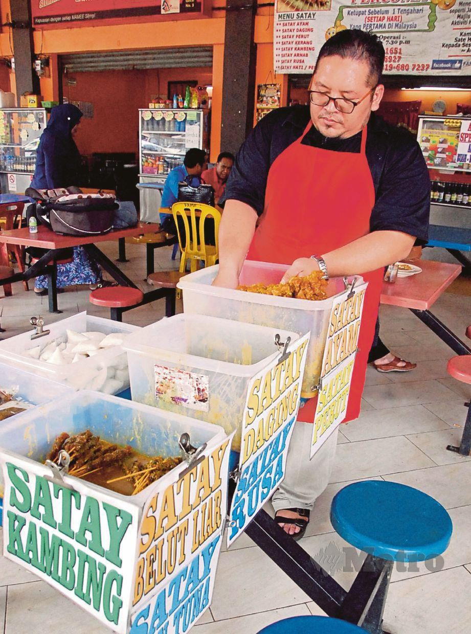 MOHD Fahmi menyediakan sate ayam dan pelbagai sate lain di gerainya di Medan Selera Pasar Menggong, Alor Gajah.