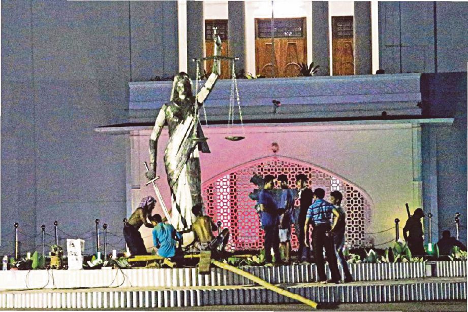 BEBERAPA pekerja dilihat melakukan proses memindahkan patung berkenaan di hadapan Mahkamah Agung di Dhaka, semalam.  - Agensi 
