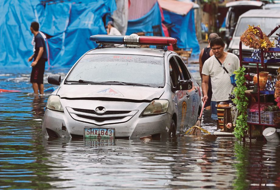 SEBUAH kereta polis terkandas di sebatang jalan yang dinaiki air akibat taufan Nock-Ten di Quezon, utara Manila semalam. - AP