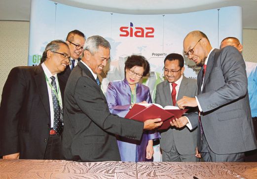 Dr Mohd Fauzi (tiga dari kiri) dan Asrul Muniff (kanan) bertukar dokumen perjanjian, semalam.