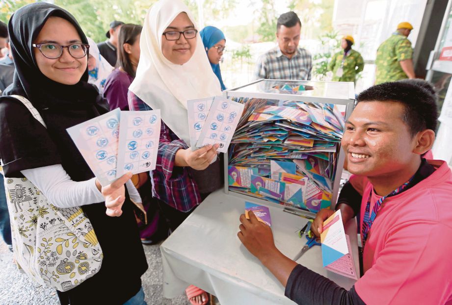 Pengunjung EMK 2018, Aishah Shafikah Jamil (kanan) bersama rakan, Nur Faizah Dayana Jaffri Johan menunjukkan pasport cabutan bertuah yang sudah dilengkapi dengan cop pengesahan untuk dimasukkan ke dalam kotak cabutan bertuah.