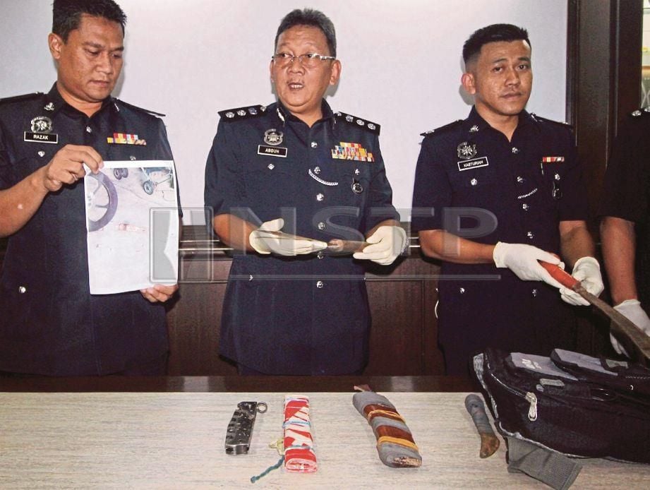 MOHD Abduh (tengah) menunjukkan senjata yang dirampas daripada suspek.