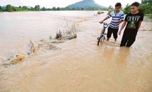 Penduduk  mengharungi banjir kilat akibat hujan lebat  di Kampung Belukar, Changlun.