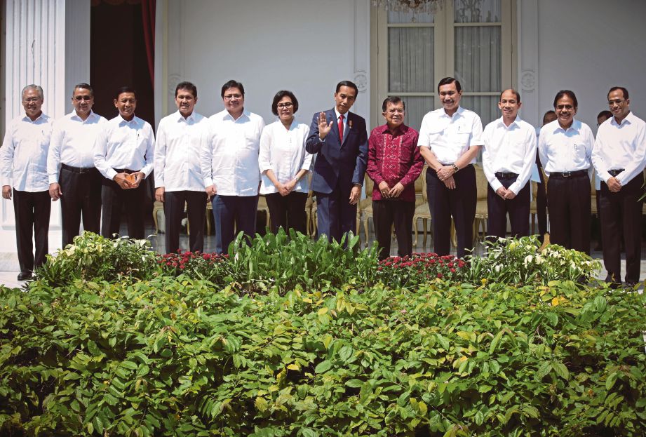 JOKOWI (berkot) dan timbalannya, Jusuf Kalla (baju merah) bergambar dengan anggota Kabinet yang baru dilantik di Istana Merdeka, Jakarta, semalam.  - EPA