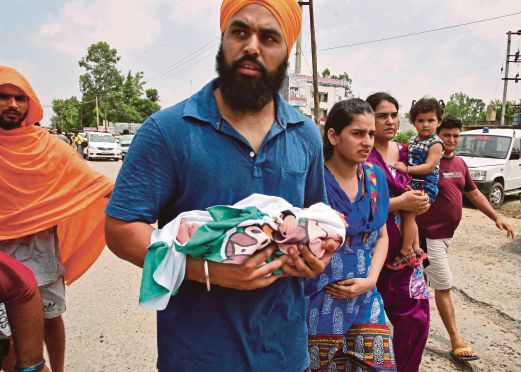 Seorang lelaki mendukung bayinya yang baru dilahirkan selepas hospital berhampiran lokasi tembakan terpaksa dikosongkan.