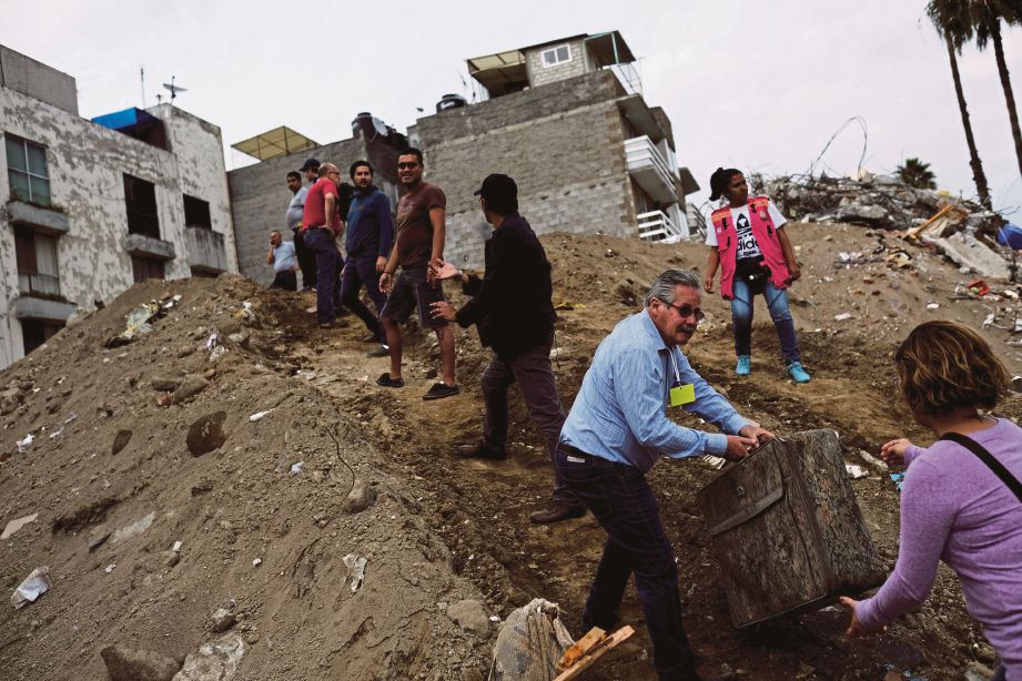 PENDUDUK mengeluarkan barangan dari kediaman mereka yang runtuh. - Reuters  