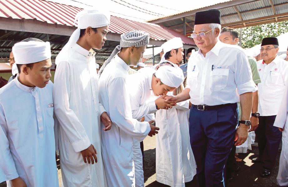 NAJIB  bersalaman dengan  pelajar pondok di Madrasah Al-Ulum Ad-Diniah Al-Usmaniah Pondok Tanjung Kapor,  semalam.