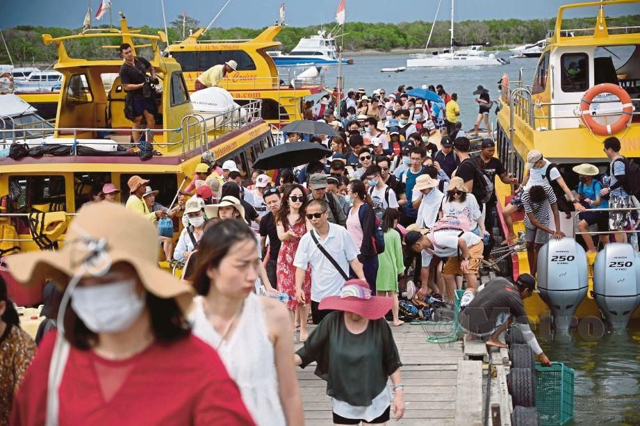 PELANCONG China memakai topeng muka ketika tiba di jeti Pulau Serangan, Denpasar, Indonesia.