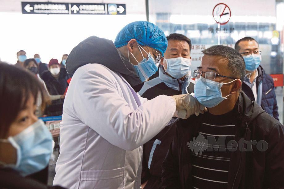 PASUKAN perubatan memeriksa suhu penumpang kapal terbang di balai pelepasan lapangan terbang di Changsa, Hunan, China.