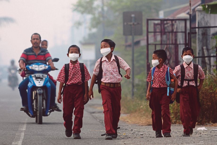 PELAJAR menggunakan topeng ketika berjalan ke sekolah di Kampung Suak Raya di Aceh Barat, semalam. - Reuters 