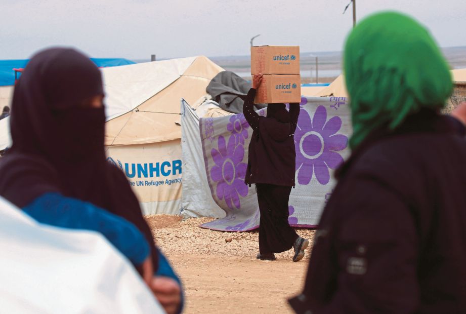 WANITA Syria yang berlindung di pusat penempatan sementara di Deir Ezzor, Syria, membawa kotak mengandungi barangan bantuan agensi PBB. - AFP 