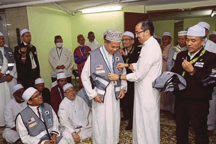 DR  Asyraf   menyerahkan vest kepada sebahagian  jemaah haji   yang dipilih sebagai Sahabat Maktab  pada  pelancaran  program   di Maktab 81. 