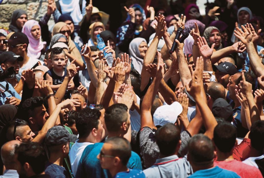 PENDUDUK Palestin meraikan ‘kemenangan’ selepas solat Zuhur yang diadakan di luar pekarangan  Al-Haram Al-Sharif di Kota Lama Baitulmaqdis, semalam. - Reuters 