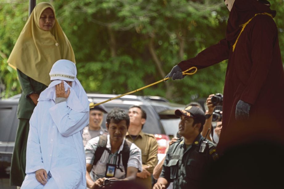 Penganut Kristian di Aceh, Tjia Nyuk Hwa, menjalani hukuman sebat, semalam. - AFP 