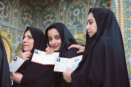 TIGA wanita Iran menunjukkan kad pengenalan ketika berbaris untuk membuang undi di Qom kelmarin.