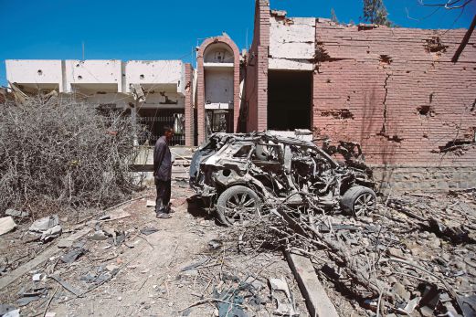 SEORANG lelaki melihat sebuah kereta yang musnah dalam satu serangan udara di Sanaa semalam.