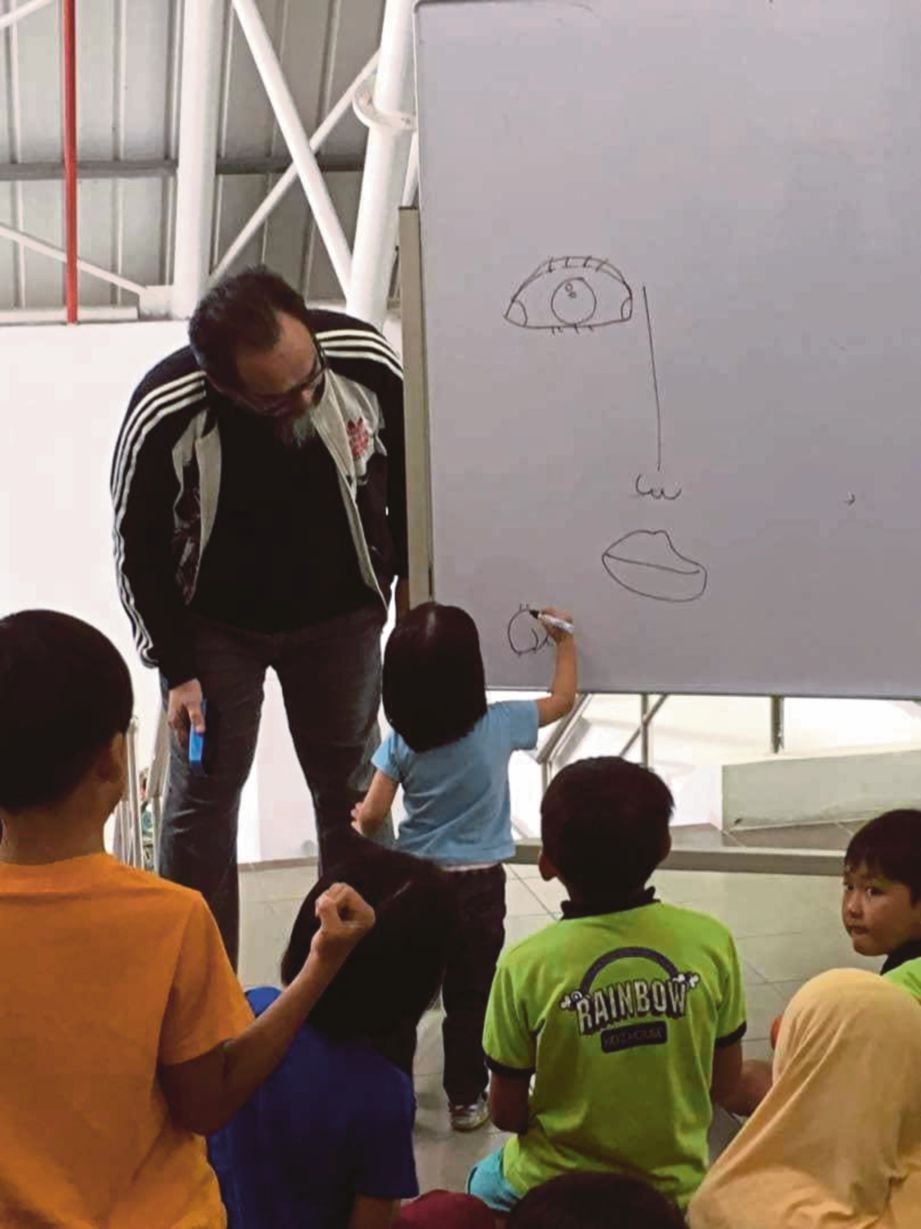 FATHUL memberi tunjuk ajar kepada kanak-kanak yang menyertai bengkel seni yang dianjurkannya. FOTO NSTP
