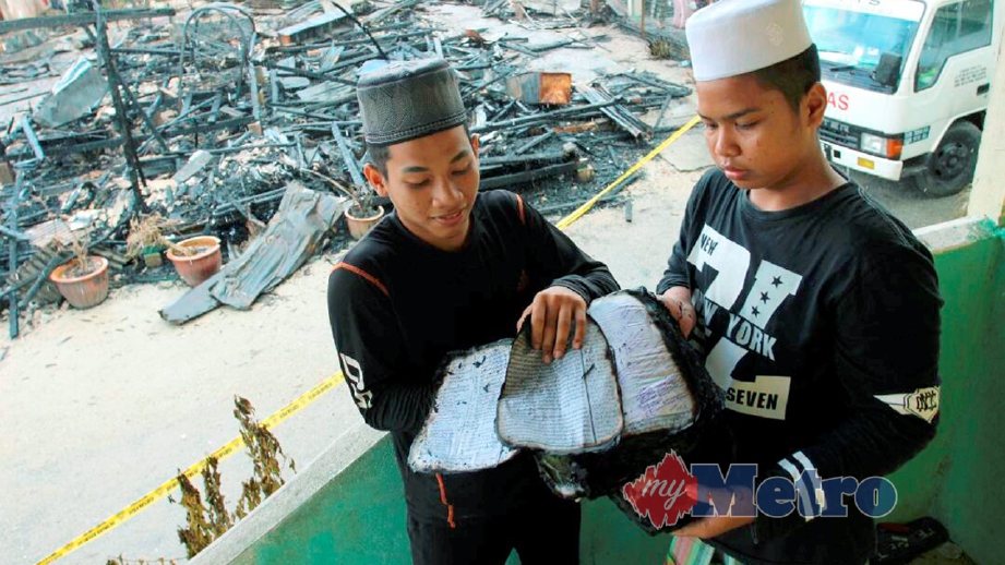 PELAJAR, Nik Mohd Nabil Nassir, 18, (kiri) dan Mohd Syahir Asri, 14, melihat kitab yang terbakar. FOTO Nik Abdullah Nik Omar