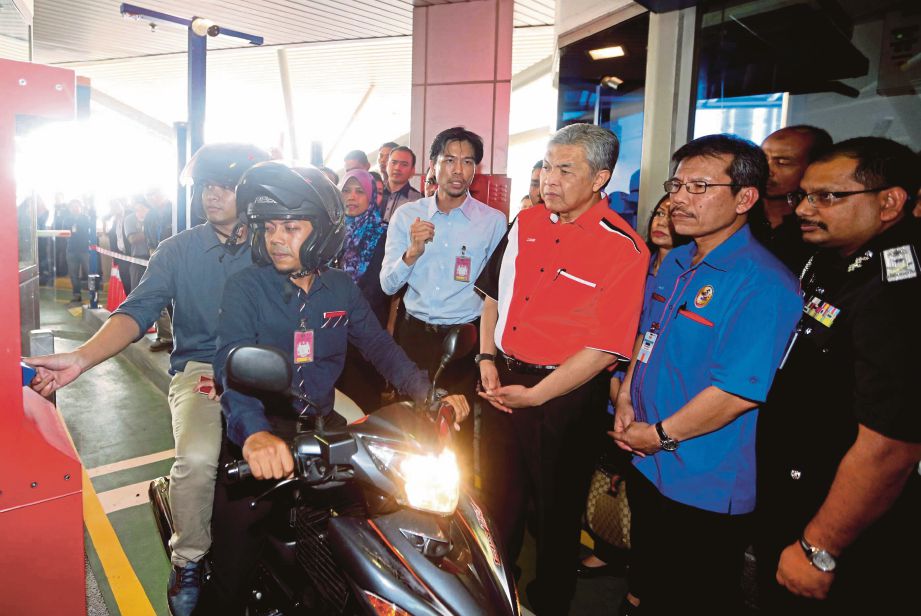 Timbalan Perdana Menteri, Datuk Seri Ahmad Zahid Hamidi melihat penunggang motosikal mengimbas kad  di BSI, semalam. 