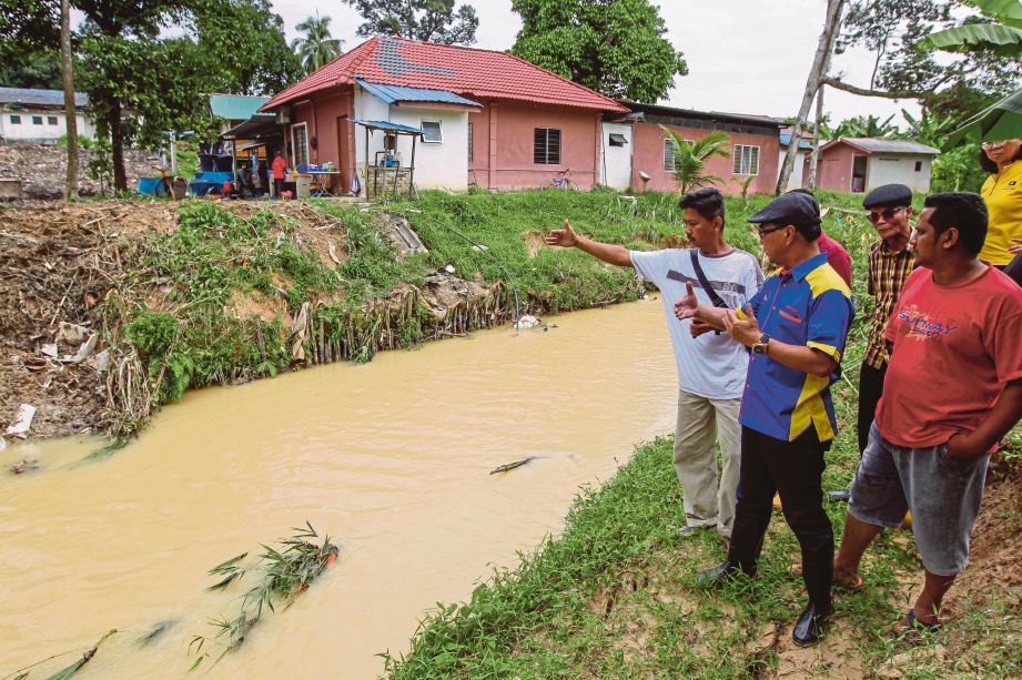  AZMAN (dua dari kiri) bersama penduduk  meninjau masalah banjir lumpur yang melanda Kampung Sungai Sekamat sejak setahun lalu.