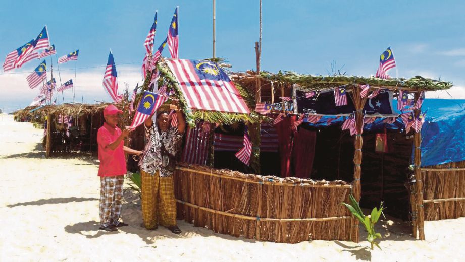 KAMAL (kiri) bersama peserta  membetulkan Jalur Gemilang yang dipasang di bangsal sempena Pesta Pantai.