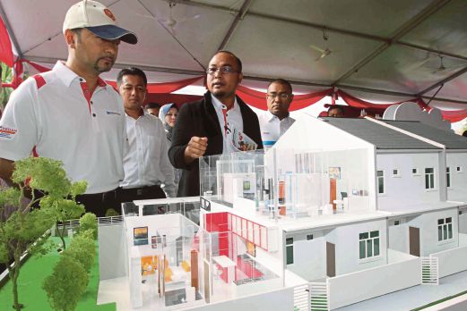 MUKHRIZ (kiri) bersama Izham Yusoff (kanan) melihat model rumah di majlis pelancaran Darulaman Perdana.