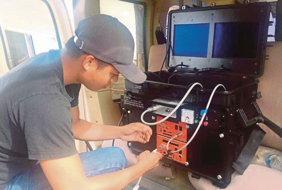   Kakitangan JHS memasang peralatan sensor untuk   pemetaan hutan di Sarawak menggunakan helikopter.  