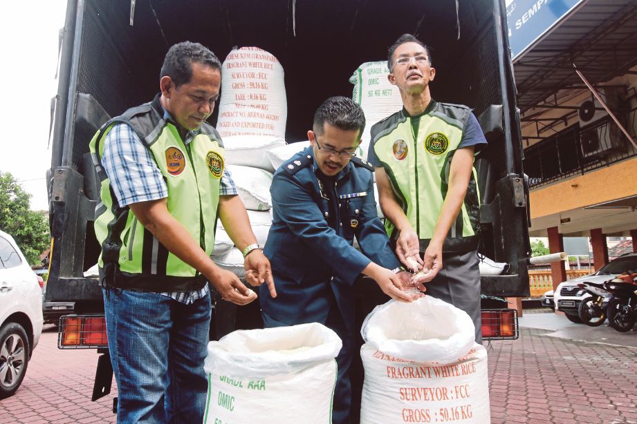MOHD Asri (tengah) bersama pegawainya menunjukkan beras yang dirampas.