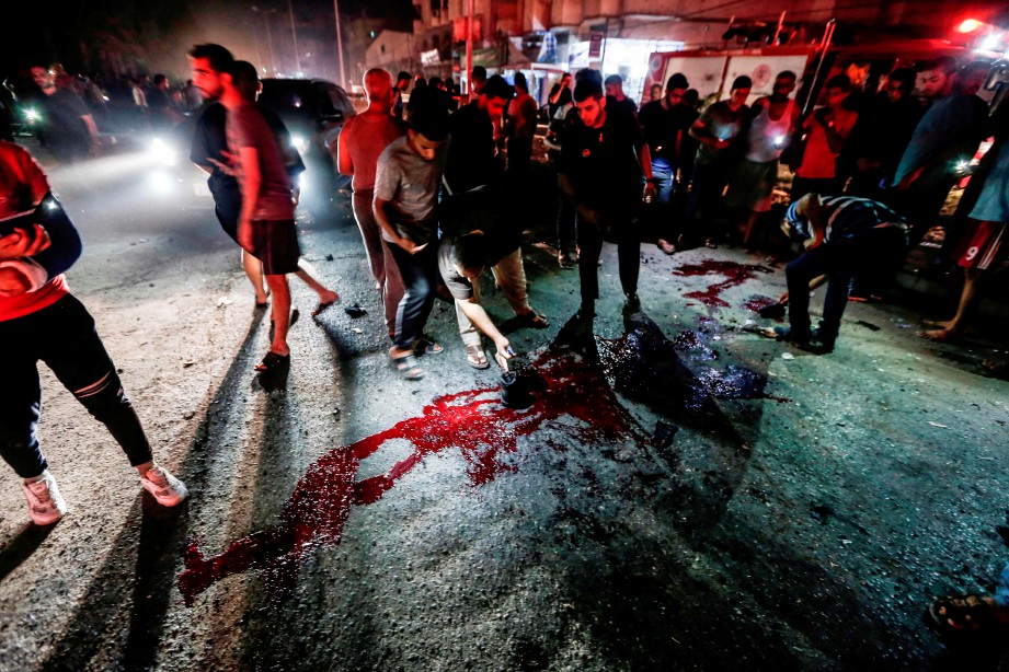 ORANG ramai melihat kesan darah di atas jalan. - AFP