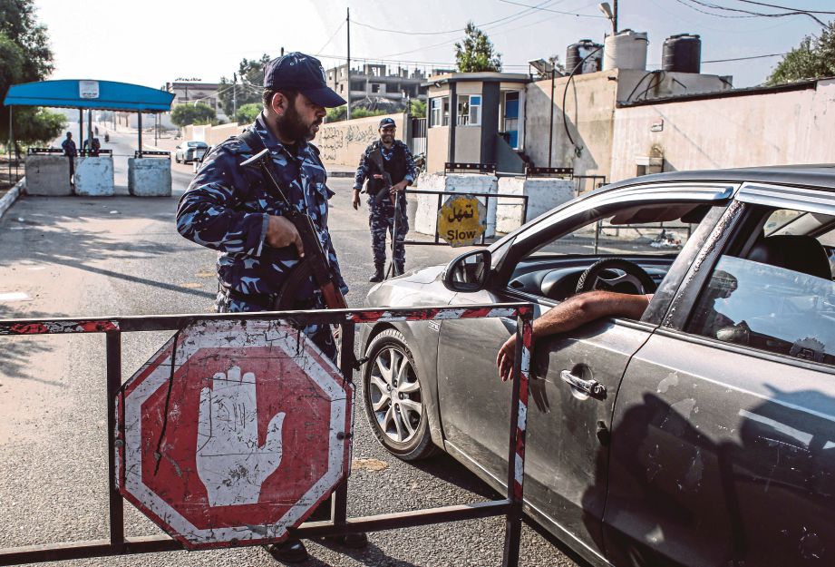 ANGGOTA keselamatan memeriksa kenderaan di  sebuah pos kawalan di Khan Younis. - Reuters