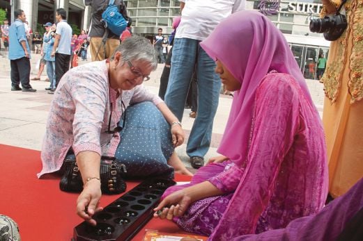 PELANCONG mencuba permainan tradisional ketika  sambutan Hari UNESCO Peringkat Kebangsaan di Kuala Lumpur.