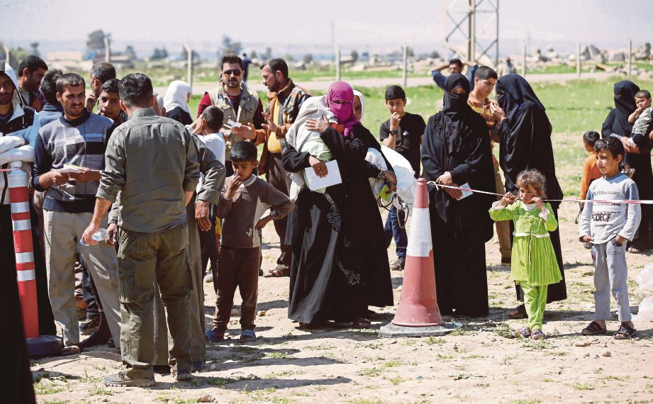 PENDUDUK Iraq yang melarikan diri dari pertempuran di barat Mosul mendapatkan bantuan kemanusiaan di kem sementara di Salamiyah, timur Mosul, semalam. - AFP