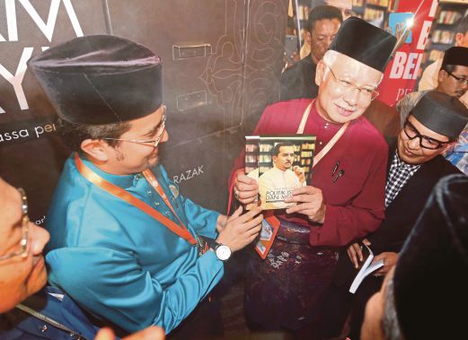  Najib  menunjukkan buku Politik Islam dan Melayu ketika majlis perasmian disaksikan  Asyraf Wajdi (kiri), sempena Perhimpunan Agung UMNO 2014 di PWTC.
