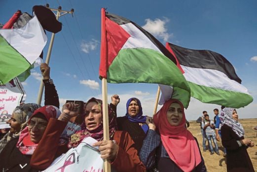PENUNJUK perasaan membawa bendera Palestin ketika melakukan demonstrasi anti-Israel berhampiran sempadan Israel dengan selatan Semenanjung Gaza, semalam. 