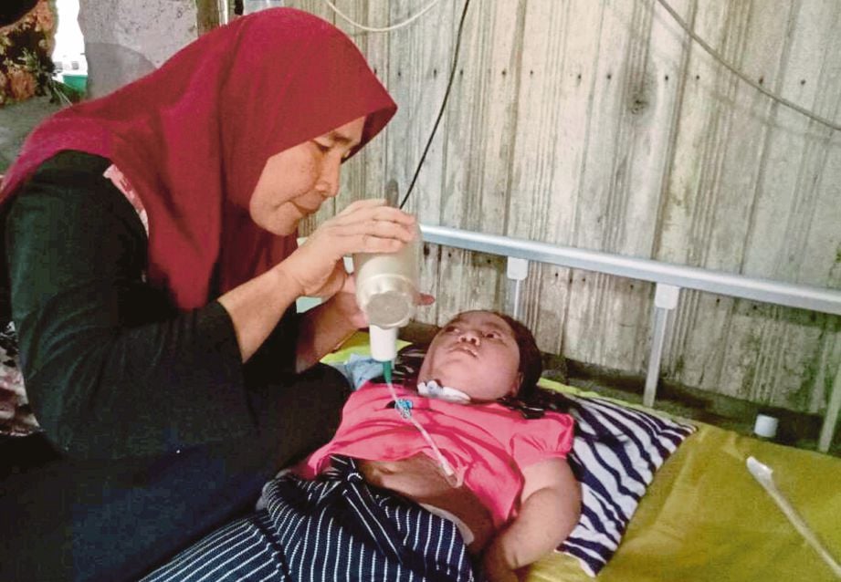 Rosnani  memberi susu kepada anak bongsunya, Adamia Fitri yang menghidap penyakit saraf otak dan paru-paru kronik di rumahnya di Kampung Banggol Judah.  