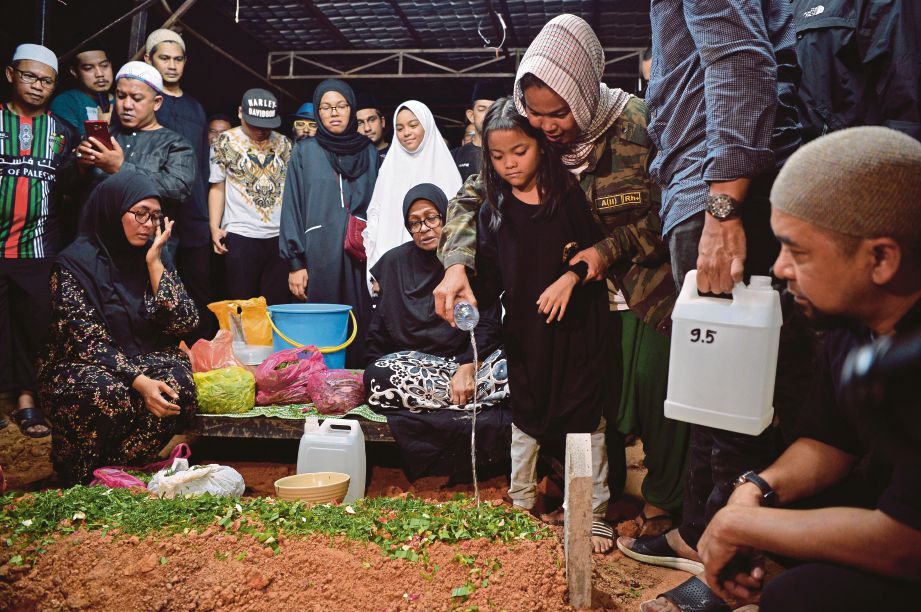 FARAH dan anak bongsunya menyiramkan air mawar ketika pengebumian jenazah Mohd Firdaus di Tanah Perkuburan Islam AU2 Keramat. FOTO Bernama