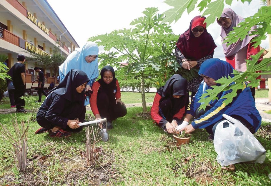 SEBAHAGIAN guru dan pelajar  menanam pokok pada  program gotong-royong di SMK Ahmad. 
