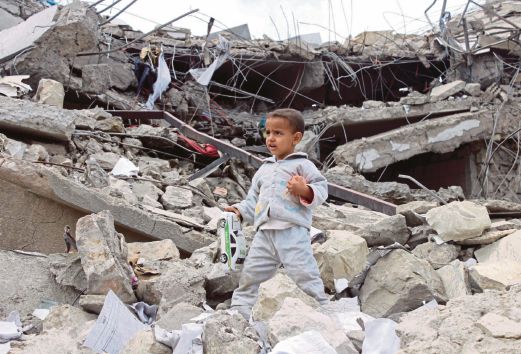 SEORANG kanak-kanak memungut permainan dari runtuhan rumahnya yang musnah dalam serangan udara di Saada, bandar di timur laut Yaman,  semalam. 
