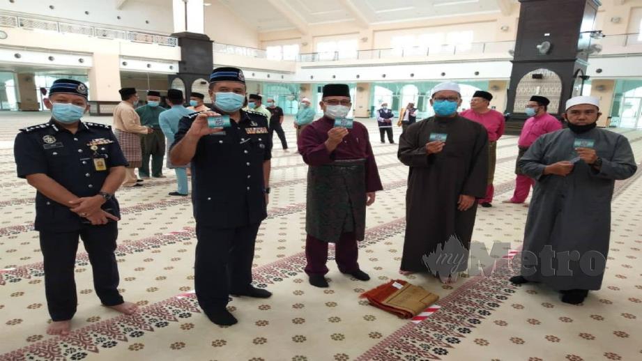SAHABUDIN (dua dari kiri) menunjukkan kupon yang digunakan pengurusan Masjid Abdul Fahim bagi mengawal kemasukan jemaah. FOTO Nur Izzati Mohamad