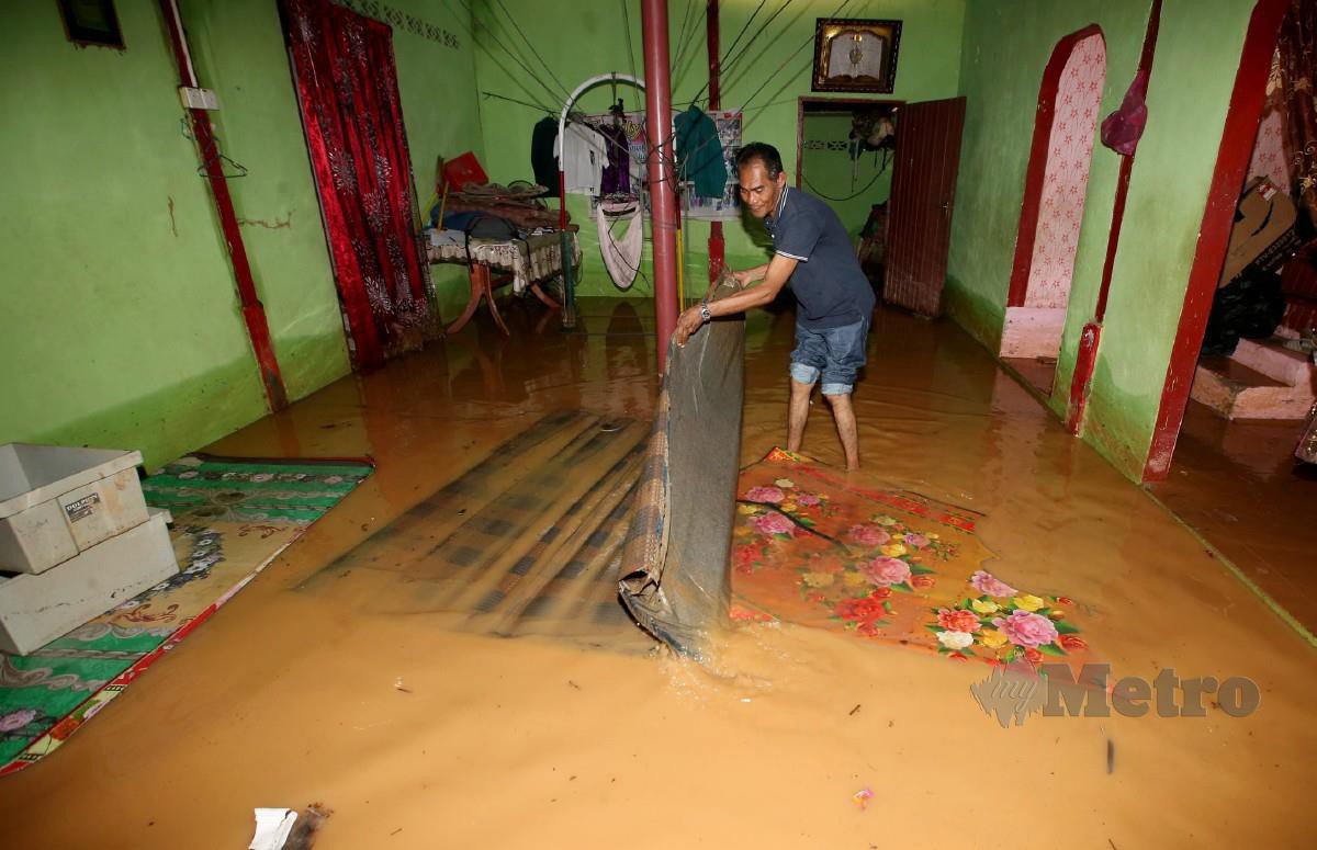 IDRIS Ismail, 50, mengemas rumahnya di Kampung Sungai Petani, Kubang Pasu yang dilanda banjir. FOTO Danial Saad.