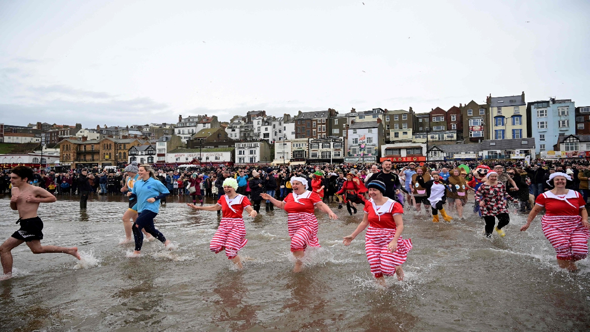 PESERTA memakai kostum berlari ke arah laut pada hari pertama Tahun Baharu sempena kutipan amal dana  di South Bay, Scarborough, England.