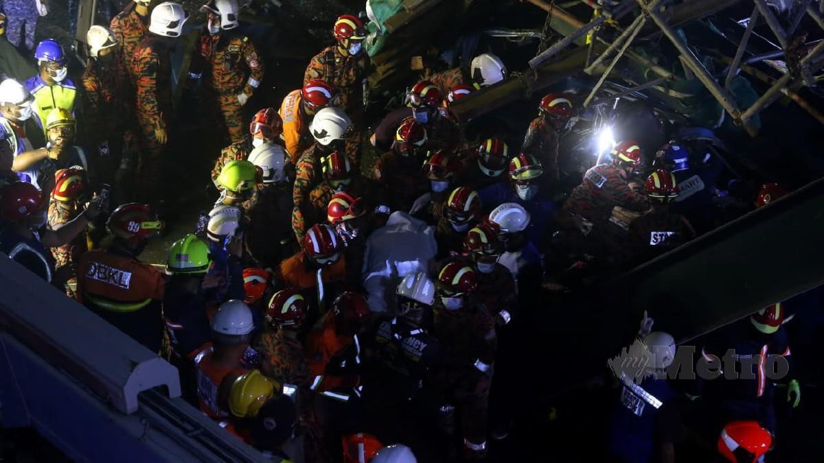 PASUKAN penyelamat membawa keluar mayat mangsa selepas van kilang dinaiki dihempap runtuhan jejambat, hari ini. FOTO HAIRUL ANUAR ABD RAHIM