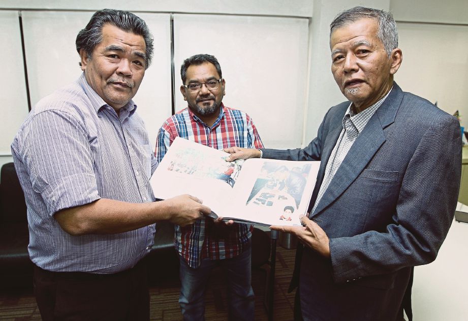  MUSTAPA (kiri) menyerahkan buku ulang tahun Harian Metro kepada Jaafar sambil disaksikan Pengerusi Yayasan Kartunis Malaysia, Mohd Desa Omar.
