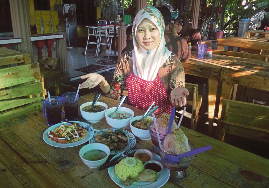  SITI Roshaida  menunjukkan menu yang dijual di gerainya di Kampung Deralik, Sitiawan.