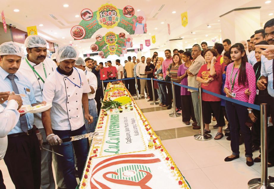 PELANGGAN turut menikmati kek simbolik ‘Fiesta Makanan 2016’ sepanjang 10 meter di Pasaraya Lulu. 