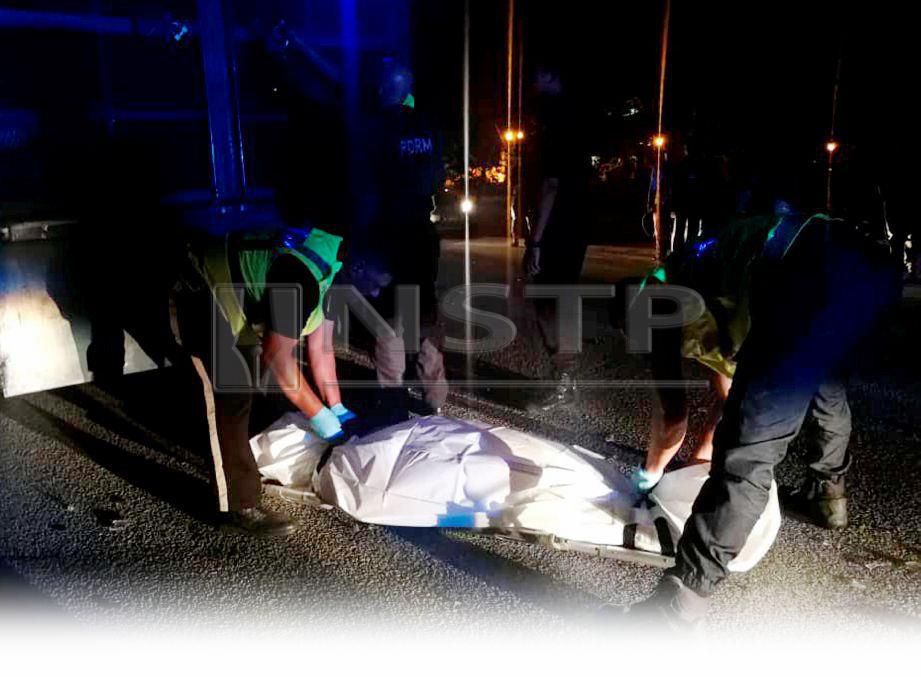 ANGGOTA polis mengangkat mayat mangsa selepas motosikal ditunggangnya melanggar kerbau. FOTO Ihsan Pembaca 