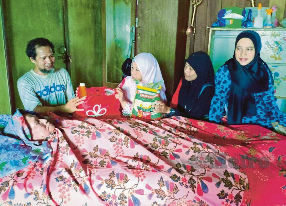 ALIAS dan ibunya Teh menerima kunjungan dan sumbangan daripada Hartini (kanan). FOTO Ahmad Rabiul Zulkifli