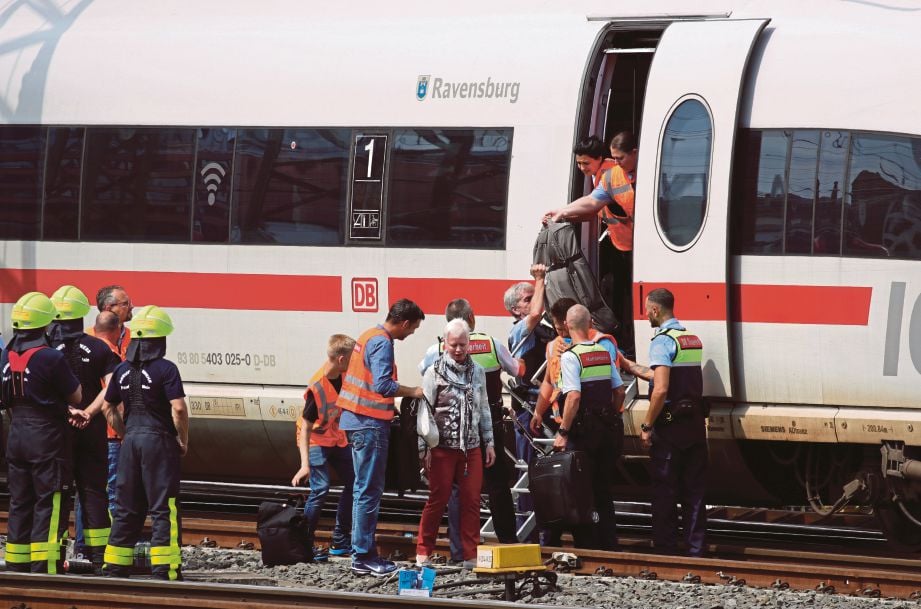 ANGGOTA penyelamat membantu penumpang turun daripada kereta api ICE. FOTO: AFP